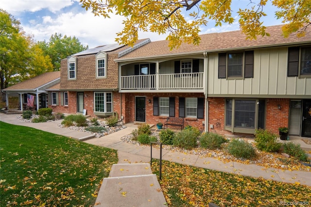 townhome / multi-family property with a front yard and solar panels