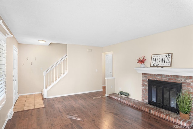 unfurnished living room featuring a brick fireplace, hardwood / wood-style floors, and a textured ceiling