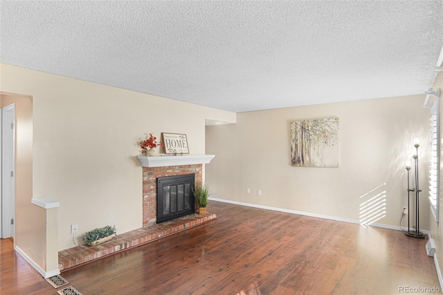 unfurnished living room featuring wood-type flooring, a fireplace, and a textured ceiling