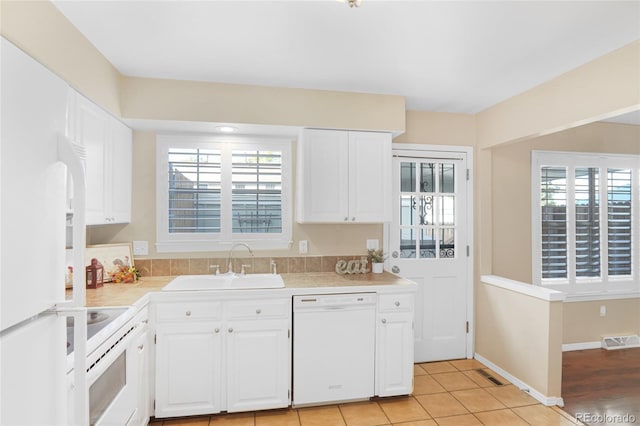 kitchen featuring white cabinetry, sink, white appliances, and a wealth of natural light