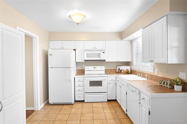 kitchen featuring white cabinetry, sink, light tile patterned floors, and white appliances