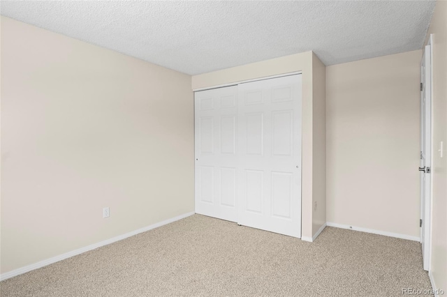 unfurnished bedroom with light carpet, a closet, and a textured ceiling