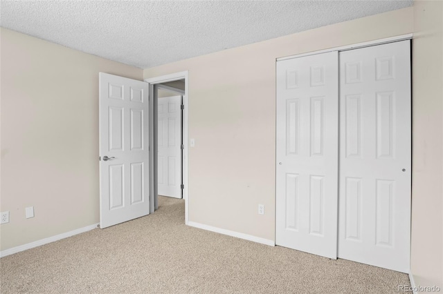 unfurnished bedroom with light carpet, a textured ceiling, and a closet