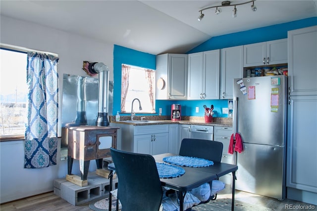 kitchen with light hardwood / wood-style floors, lofted ceiling, sink, stainless steel refrigerator, and white cabinetry