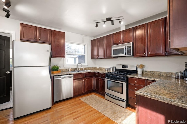 kitchen featuring stone countertops, sink, stainless steel appliances, and light hardwood / wood-style flooring