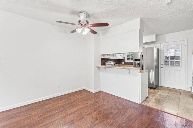 14465 E Hawaii Cir Unit A, Aurora, CO 80012 - kitchen with a peninsula, stainless steel fridge, a breakfast bar, light wood-type flooring, and ceiling fan