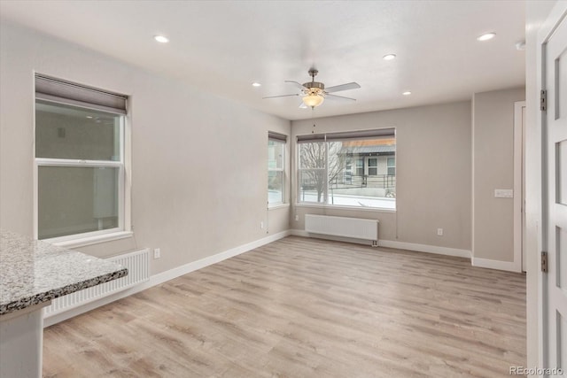 empty room with ceiling fan, radiator heating unit, and light hardwood / wood-style floors