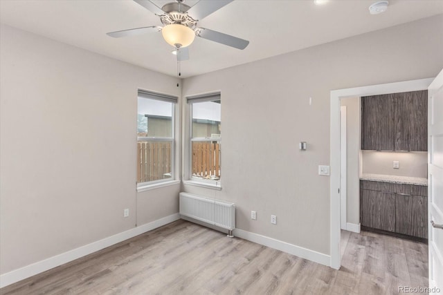 unfurnished room featuring radiator heating unit, light hardwood / wood-style flooring, and ceiling fan