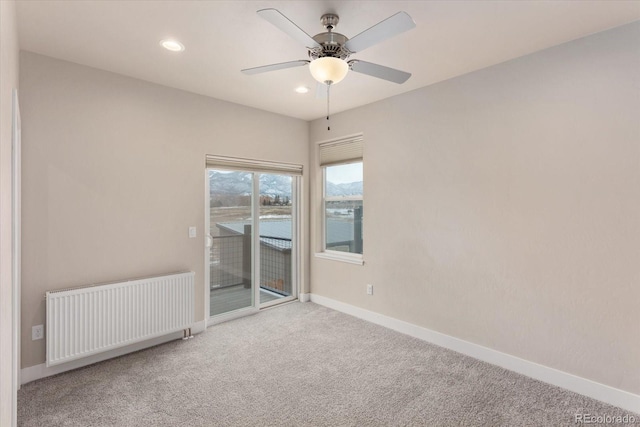 empty room with carpet, radiator heating unit, a water view, and ceiling fan