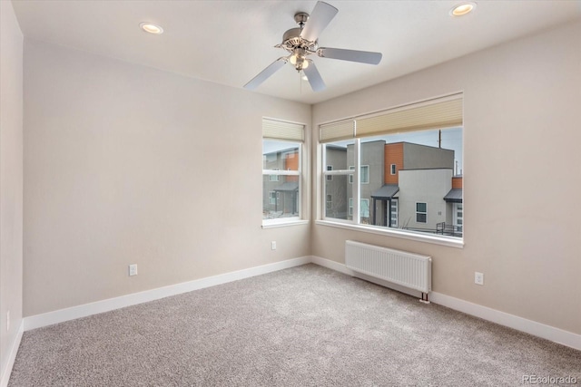 carpeted empty room featuring ceiling fan and radiator heating unit