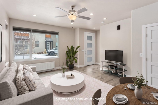 living area with light wood-type flooring, baseboards, radiator heating unit, and recessed lighting