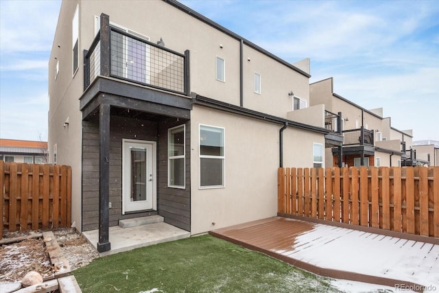 back of property featuring fence, a balcony, and stucco siding