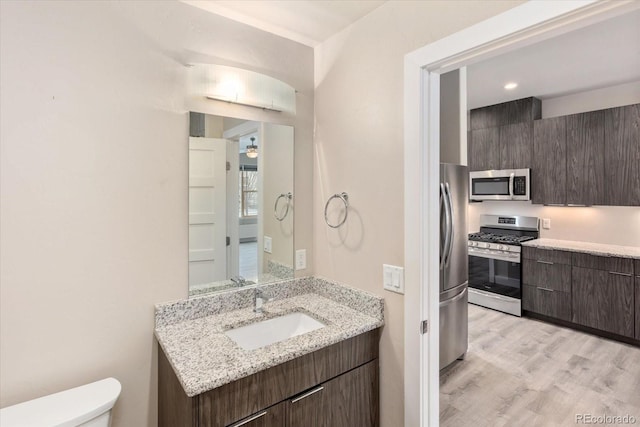 bathroom with vanity, wood finished floors, and toilet