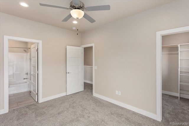 unfurnished bedroom featuring baseboards, a walk in closet, and carpet flooring