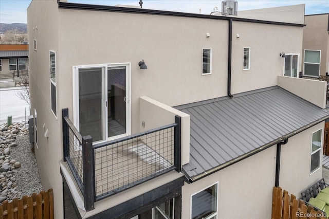 back of property with fence, a balcony, and stucco siding