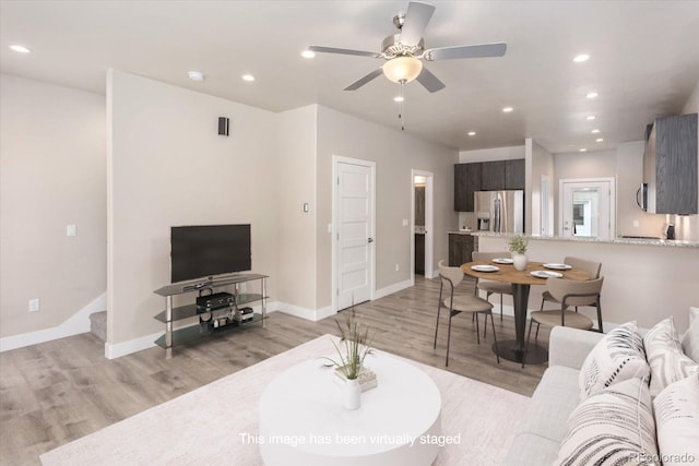 living room with light wood-style flooring, recessed lighting, a ceiling fan, baseboards, and stairway