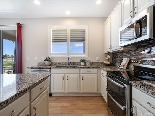 kitchen featuring appliances with stainless steel finishes, sink, white cabinets, and dark stone counters