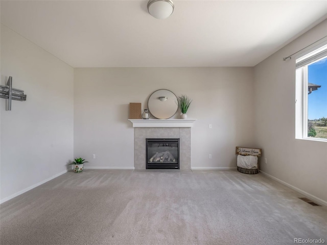 unfurnished living room with light colored carpet and a tile fireplace