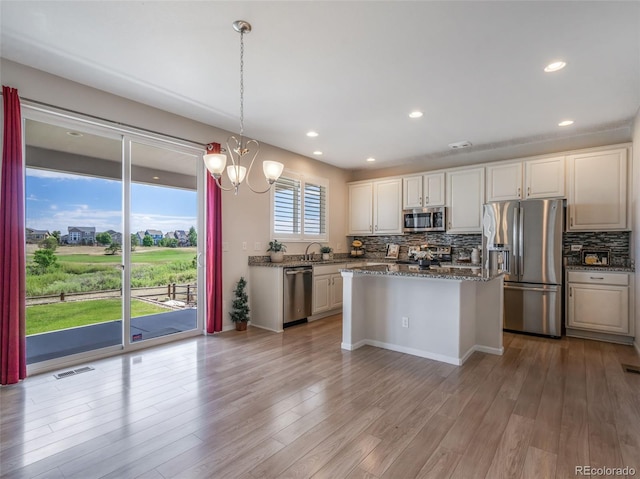 kitchen featuring decorative light fixtures, dark stone countertops, appliances with stainless steel finishes, decorative backsplash, and white cabinets