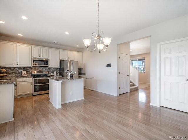 kitchen featuring pendant lighting, a kitchen island, stainless steel appliances, and stone countertops