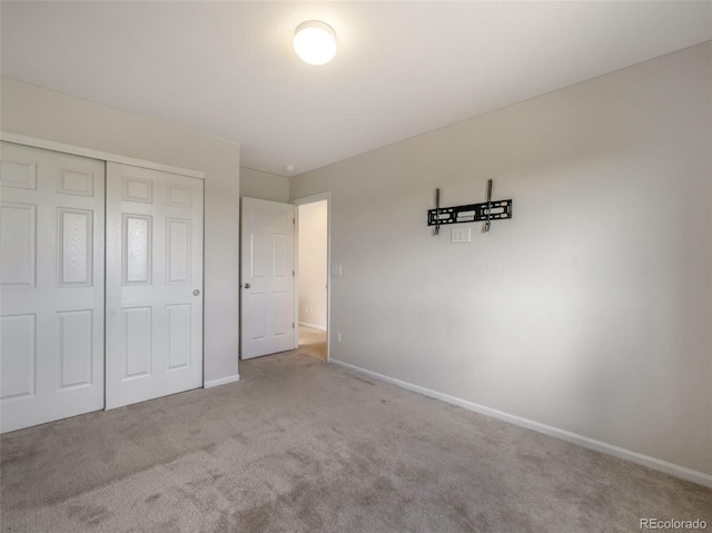 unfurnished bedroom featuring light carpet and a closet