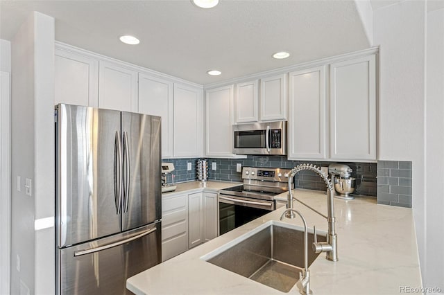 kitchen featuring stainless steel appliances, white cabinetry, tasteful backsplash, and sink