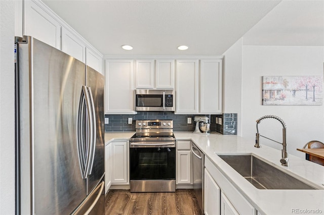 kitchen with white cabinetry, stainless steel appliances, backsplash, dark wood-type flooring, and sink