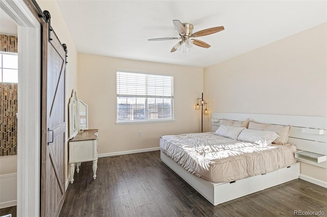 bedroom featuring ceiling fan, dark hardwood / wood-style flooring, and a barn door