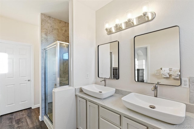 bathroom with hardwood / wood-style floors, a shower with door, and vanity