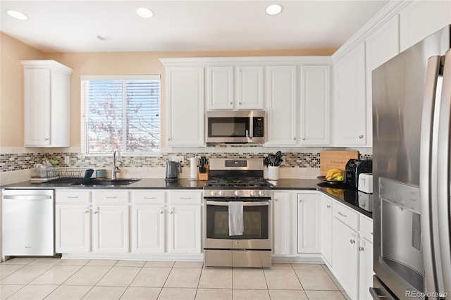 kitchen featuring light tile patterned floors, white cabinetry, appliances with stainless steel finishes, decorative backsplash, and sink