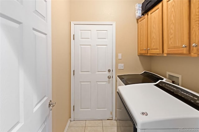 laundry room featuring cabinets, light tile patterned floors, and washer and clothes dryer