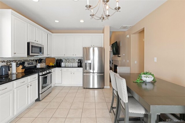 kitchen featuring decorative light fixtures, light tile patterned floors, white cabinets, and stainless steel appliances