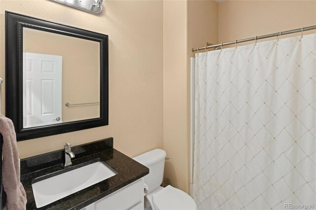 bathroom featuring toilet, walk in shower, and vanity