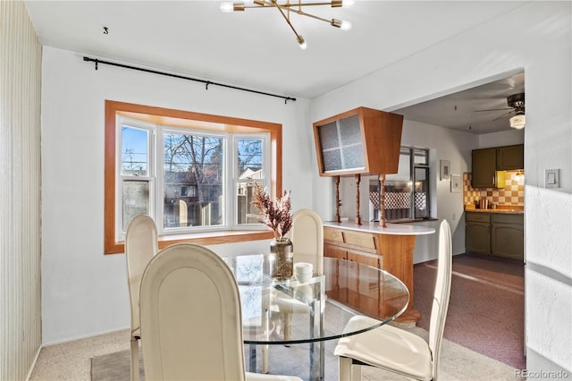 carpeted dining room featuring ceiling fan with notable chandelier