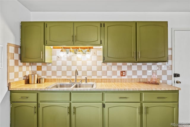 kitchen with backsplash, light countertops, green cabinets, and a sink