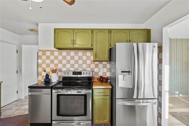 kitchen with tile patterned flooring, tasteful backsplash, green cabinetry, and stainless steel appliances