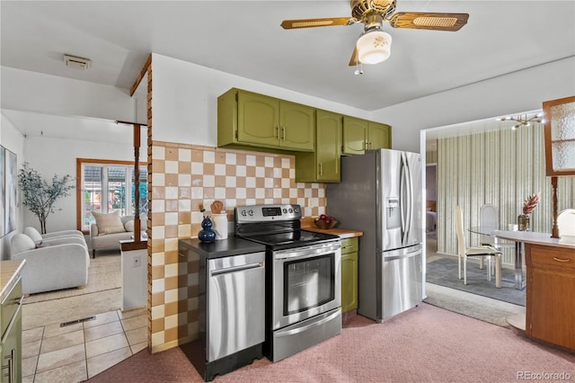 kitchen featuring light carpet, appliances with stainless steel finishes, green cabinetry, decorative backsplash, and ceiling fan