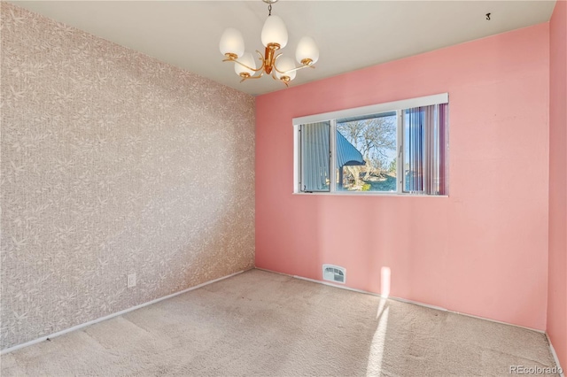 carpeted empty room with visible vents and an inviting chandelier