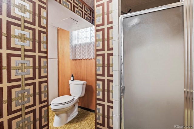 bathroom with a stall shower, toilet, and wallpapered walls