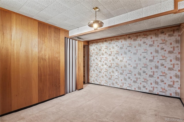 unfurnished room featuring baseboards, light carpet, and wooden walls