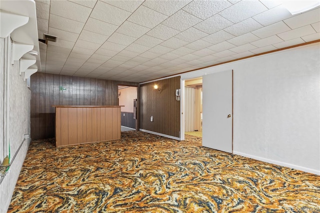 unfurnished living room featuring wooden walls and baseboards