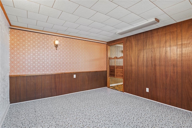 unfurnished room with crown molding, wooden walls, a wainscoted wall, and carpet floors