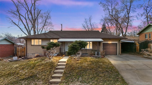 view of front of property with fence, brick siding, a garage, and driveway