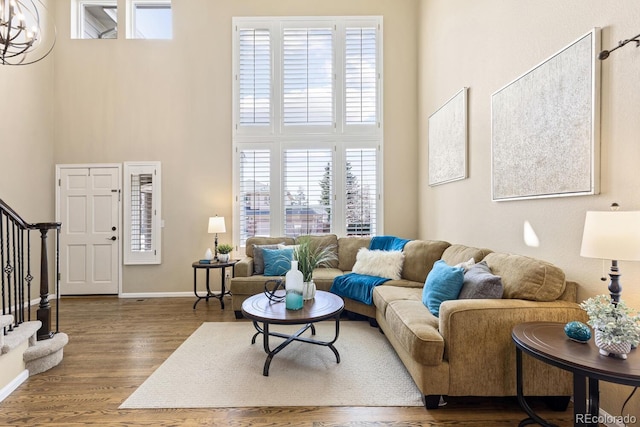 living room featuring a towering ceiling, a chandelier, and hardwood / wood-style flooring