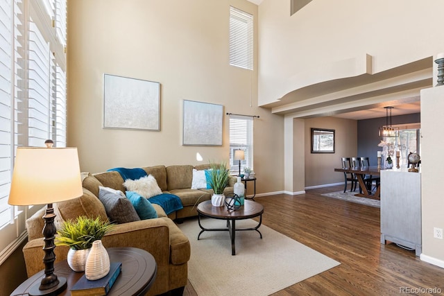 living room featuring a high ceiling, dark wood-type flooring, and a chandelier