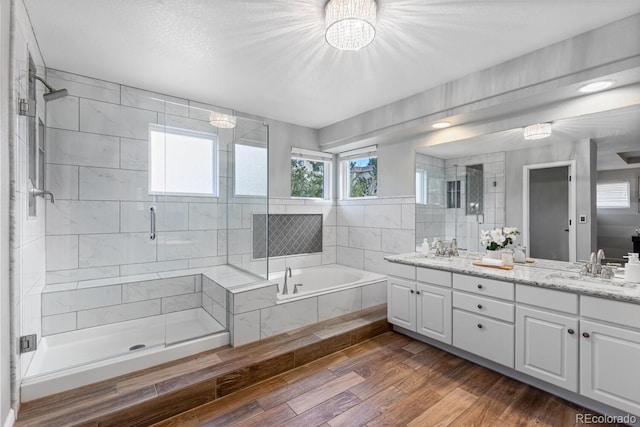 bathroom with plenty of natural light, separate shower and tub, wood-type flooring, and vanity