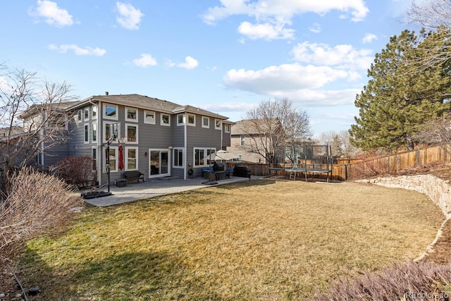 back of property featuring a trampoline, a yard, and a patio area