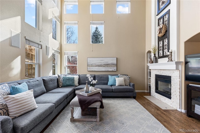 living room with wood-type flooring, a towering ceiling, and a fireplace