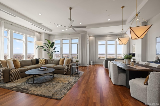 living area with dark wood finished floors, ceiling fan, and a healthy amount of sunlight