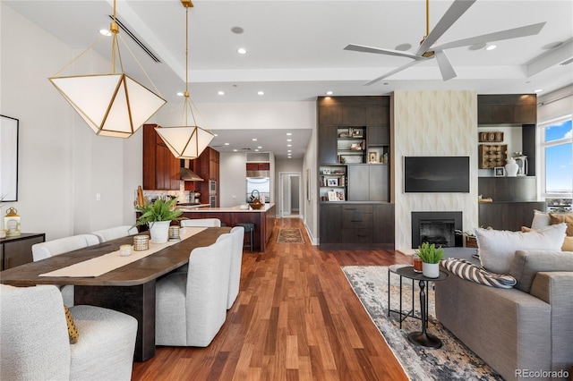 living area featuring recessed lighting, ceiling fan, a large fireplace, and wood finished floors